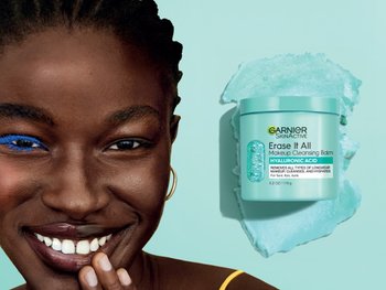 Dark skinned model with makeup removed on half of face next to Garnier Makeup Cleansing Balm with Hyaluronic Acid