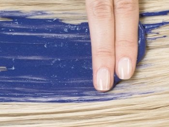 Two fingers striking blue conditioner on freshly bleached hair.