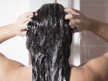 Woman washing her long curly hair in the shower.