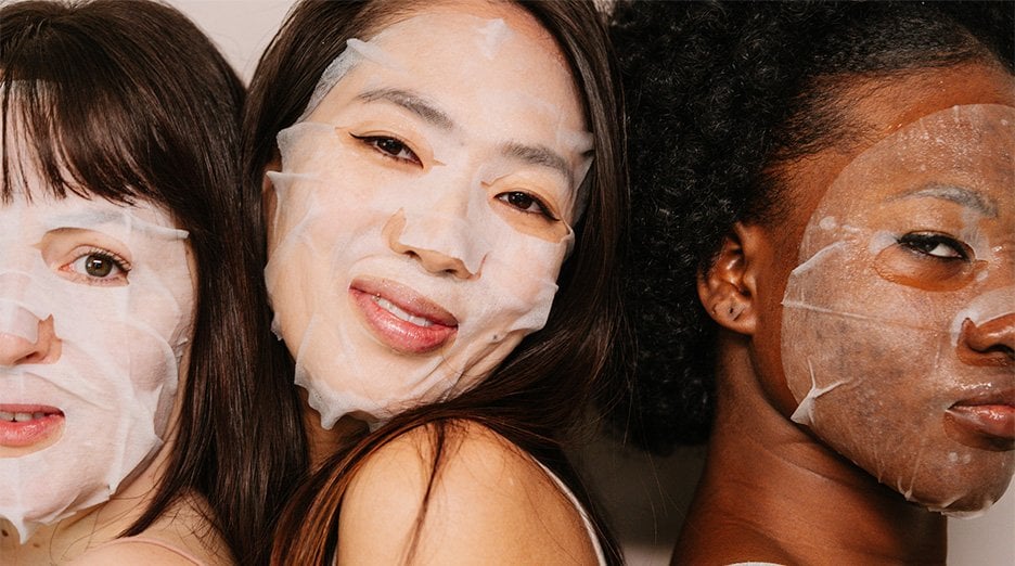 Three women with white sheet masks on their faces.