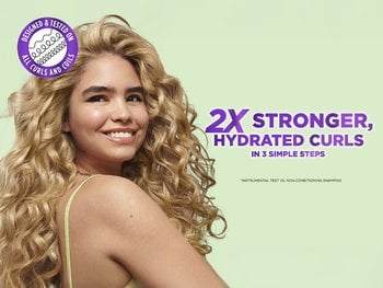 Girl with 3C curls smiling swinging her head to the side.