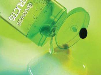 A Garnier Sleek & Shine shampoo bottle dispensing out product.