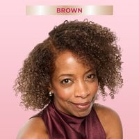 A smiling woman with shoulder-length, curly brown hair, looking directly at the viewer. A banner at the top indicates ‘Brown,' suggesting a hair color result.