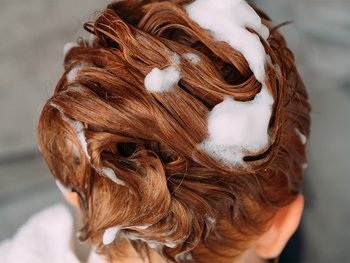 Woman washing her dyed hair with shampoo.